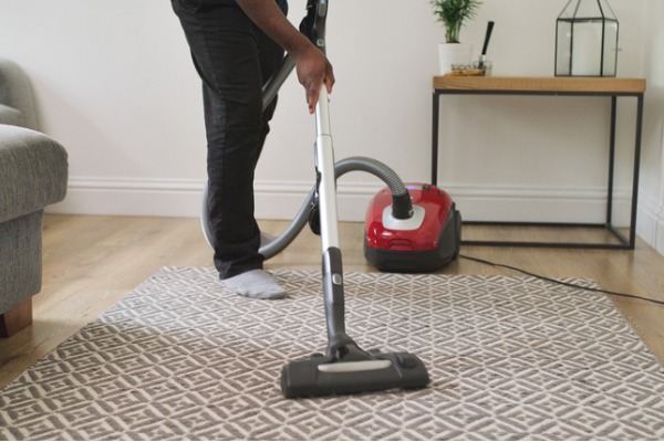 man stofzuigt parket met sledestofzuiger